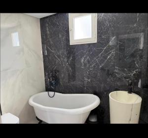 a bathroom with a white tub and a black wall at Vue Mer in Hammamet Nord +5 photos