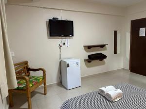 a room with a small refrigerator and a tv on the wall at Chico de Sá Pousada in Pirenópolis