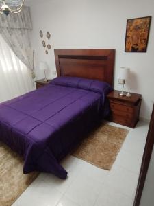 a bedroom with a purple bed and a night stand at Piso de Verano in O Grove