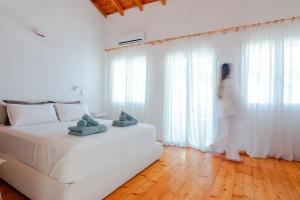 a woman standing in a bedroom looking out the window at Kooreloo Airy Loft in Koroni