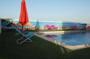 una piscina con sillas, una sombrilla y una piscina en Hotel Fleur De Lys Almadies, en Dakar