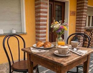 a wooden table with croissants and coffee on it at Arturs B&B Roveredo in Roveredo