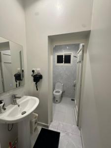 a white bathroom with a sink and a toilet at Bloom Home in Al Khobar