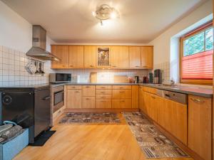 eine Küche mit Holzschränken und einem schwarzen Kühlschrank in der Unterkunft Summa Haisl in Embach