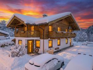 Ein schneebedecktes Haus vor dem Hintergrund eines Sonnenuntergangs in der Unterkunft Summa Haisl in Embach