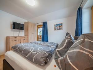 ein Schlafzimmer mit Bett, Fernseher und blauen Vorhängen in der Unterkunft Summa Haisl in Embach