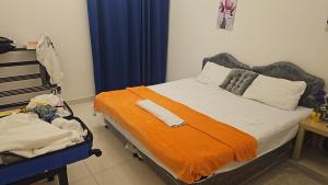 a bedroom with a bed with an orange blanket at Alkhuwir AlsumouTower in Muscat