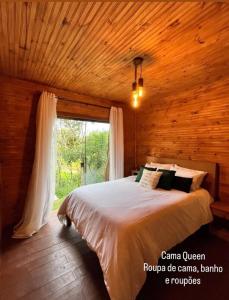 a bedroom with a large bed in a wooden room at Cabana do Mato com ofurô, cesta para café da manhã e pet friendly in Gonçalves
