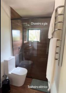 a bathroom with a white toilet and a window at Cabana do Mato com ofurô, cesta para café da manhã e pet friendly in Gonçalves +43 photos