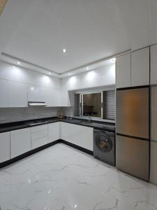 a kitchen with white cabinets and a washer and dryer at Plage & Confort in Fnidek +11 photos