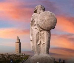a statue with a lighthouse in the background at Pensión montoxo in Cedeira
