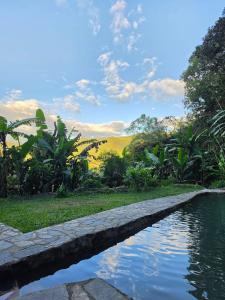 a pool of water in front of a garden at Refugio en la naturaleza in La Vega