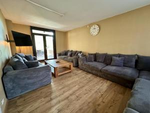 a living room with couches and a clock on the wall at Aux Berges du Lac in Jalhay
