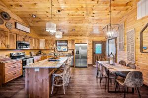 a kitchen with a long table with chairs and a refrigerator at Top Rated Modern 3BD |Secluded |Fire Pit |Arcade in Sevierville