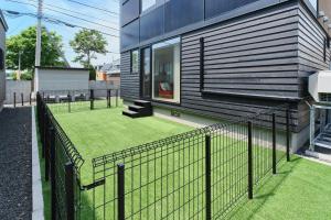 a fence in front of a house with grass at 藤乃宿 Villa Moere モエレ沼公園すぐ 愛犬と一緒に泊まれる新築1棟貸し in Sapporo