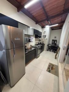 a large kitchen with a stainless steel refrigerator at Sussurros do Mar in Bertioga