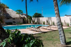a swimming pool with two chairs and a house at Pousada Estação Cajueiro in São Miguel do Gostoso