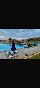 two lounge chairs and an umbrella next to a swimming pool at Lavista 7 in Ain Sokhna +10 photos