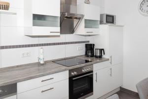 a kitchen with white cabinets and a stove top oven at Residenz Cuxhaven Döse, Ankerplatz in Döse