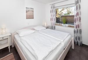 a white bedroom with a bed and a window at Residenz Cuxhaven Döse, Ankerplatz in Döse