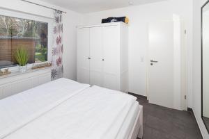 a white bedroom with a large bed and a window at Residenz Cuxhaven Döse, Ankerplatz in Döse +8 photos