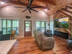 a living room with a couch and a ceiling fan at Hot Tub Cabin + Screened Porch | Red River Gorge in Beattyville