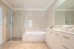 a white bathroom with a shower and a sink at Kookora Suites in Griffith +15 photos