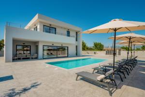 a villa with a swimming pool and umbrellas at Nimar Villas in Gaïtánion