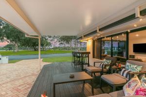 a patio with chairs and tables and a tv at Salthill in Tweed Heads