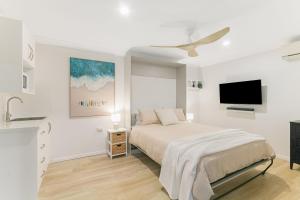 a white bedroom with a bed and a flat screen tv at Salthill in Tweed Heads +18 photos