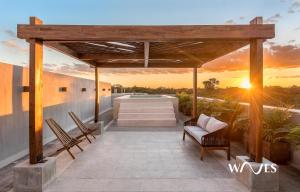 a patio with chairs and a sunset in the background at Villa morada in Tulum