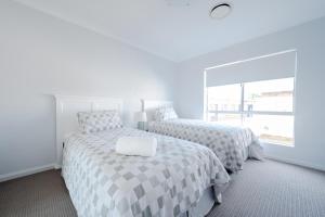 two beds in a white room with a window at Kookora Suites in Griffith
