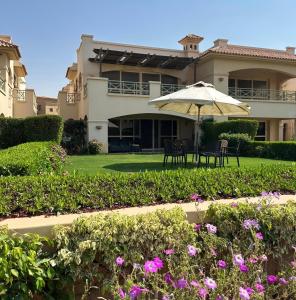 a house with a table and an umbrella in the yard at Lavista 7 in Ain Sokhna