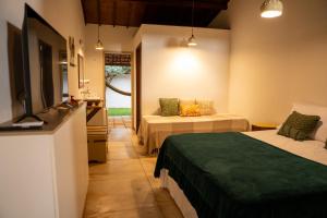 a hotel room with two beds and a television at Pousada Estação Cajueiro in São Miguel do Gostoso