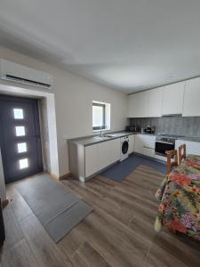 a kitchen with white cabinets and a sink and a table at Casa da Mexieira em Ponte da Barca in Ponte da Barca