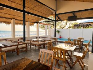 a restaurant with tables and chairs and the beach at Hotel Yaltas Inn in Tola