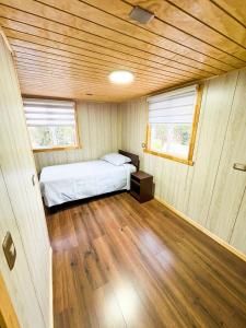 a bedroom with a bed in a room with wooden floors at Cabañas Costanera Puyuhuapi in Puerto Puyuhuapi