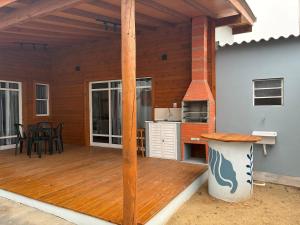 a patio with a wooden deck with a kitchen at Casa Brisa - Las Caracolas in Rio Grande