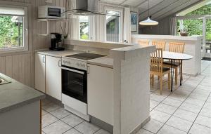 a kitchen with a stove and a table in it at Holiday Home Blåbærvangen V in Oxbøl