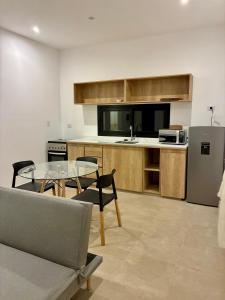 a kitchen with a glass table and a refrigerator at Plaza Suites Cafayate in Cafayate