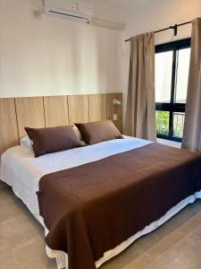 a large bed in a bedroom with a large window at Plaza Suites Cafayate in Cafayate