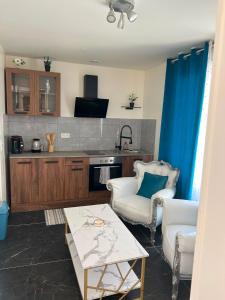 a kitchen with two white chairs and a table at Résidence les Jardins Secret in Romilly-sur-Seine