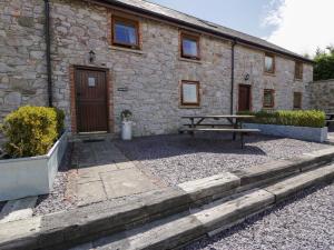 a stone house with a picnic table in front of it at Beudy Bach in Abergele