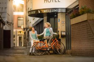 two women standing next to a bike on a street at Hotel de Duif Lisse - Keukenhof in Lisse