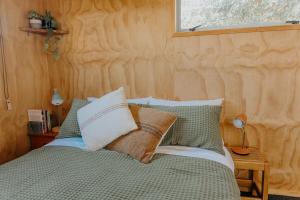a bedroom with a bed with green and white pillows at Warm & Cosy Studio Cabin in Hamilton