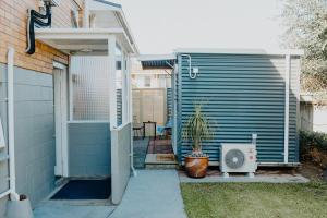 a house with a door and a plant in a yard at Warm & Cosy Studio Cabin in Hamilton