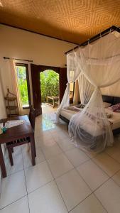 a bedroom with two beds and a chair and a table at Mango Moon in Pemuteran