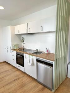 a kitchen with white cabinets and a stainless steel sink at Sitka1 apartment in Trenčín