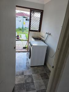 eine Waschmaschine und ein Trockner in einem Waschraum mit Fenster in der Unterkunft Wattle Close - Room in a Shared house in Kelmscott + 1 Foto