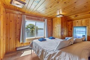 a bed in a wooden room with a window at Riverside Cabin with Private Fishing Access! in Pulaski